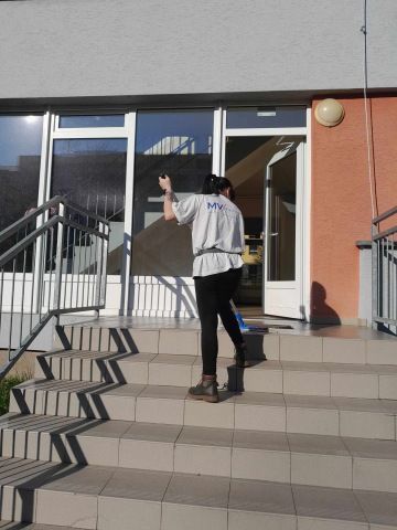 Pracovnice MV Facility vytírá venkovní schodiště u vstupu do bytového domu
